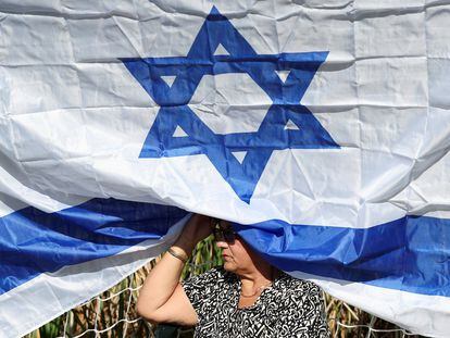 A woman under an Israeli flag during a ceremony commemorating the victims of the Hamas attack at Kibbutz Gezer.