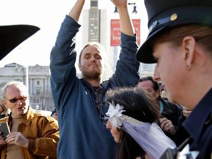 David DePape, center, records Gypsy Taub being led away by police after her nude wedding outside City Hall on Dec. 19, 2013, in San Francisco.