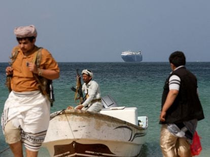 Armed men stand on the beach as the Galaxy Leader commercial ship, seized by Yemen's Houthis last month, is anchored off the coast of Al-Salif, Dec. 5, 2023.