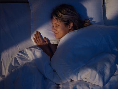 A young woman smiles while sleeping at night.