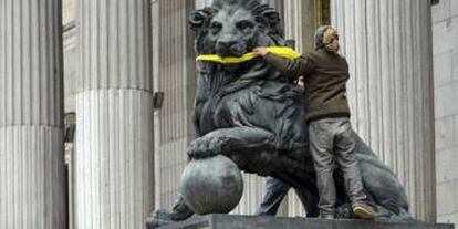 A Greenpeace activist gags one one the stone lions presiding over the Spanish Congress to protest the Citizen Safety Law.