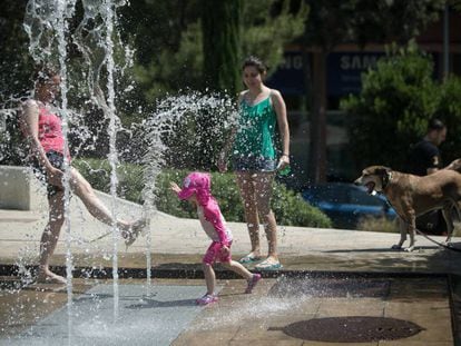 A family plays in a water fountain in Barcelona.