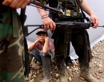 A boy sits among a group of FARC guerrillas in San Vicente del Caguán, in 2000.