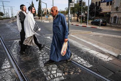 Dos ortodoxos y un musulmán se cruzan por la calle que separa la parte este de la oeste de Jerusalén.