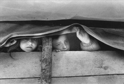 Two Kosovar Albanian refugee girls look out from inside a covered wagon in Morina, Albania, April 1999.