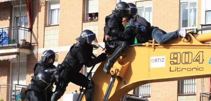 Police clash with residents who climbed on to the digger that demolished the building.