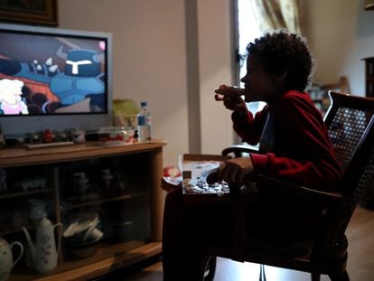 A youngster eats a slice of pizza in his home in Madrid.