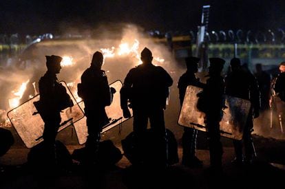 French gendarmes silhouetted by a lit bonfire, secure the area after the evacuation of the access to the oil terminal on March 21, 2023, in Donges, western France, a few days after the French government pushed a pensions reform through parliament without a vote, using the article 49.3 of the constitution. 