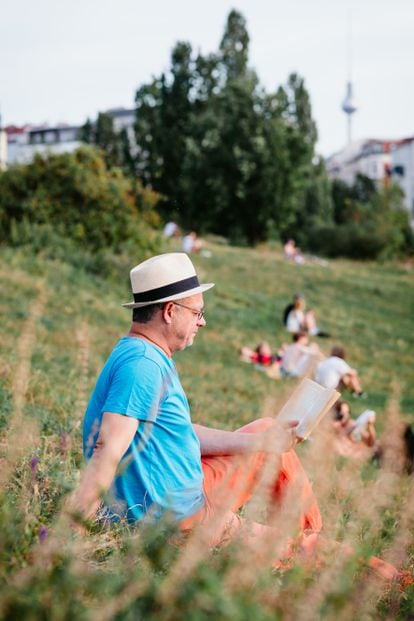 A man reads in Berlin's Mauerpark, with the Alexanderplatz television tower in the background.