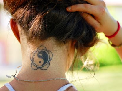 A girl shows the tattoo se has on the back of her neck.