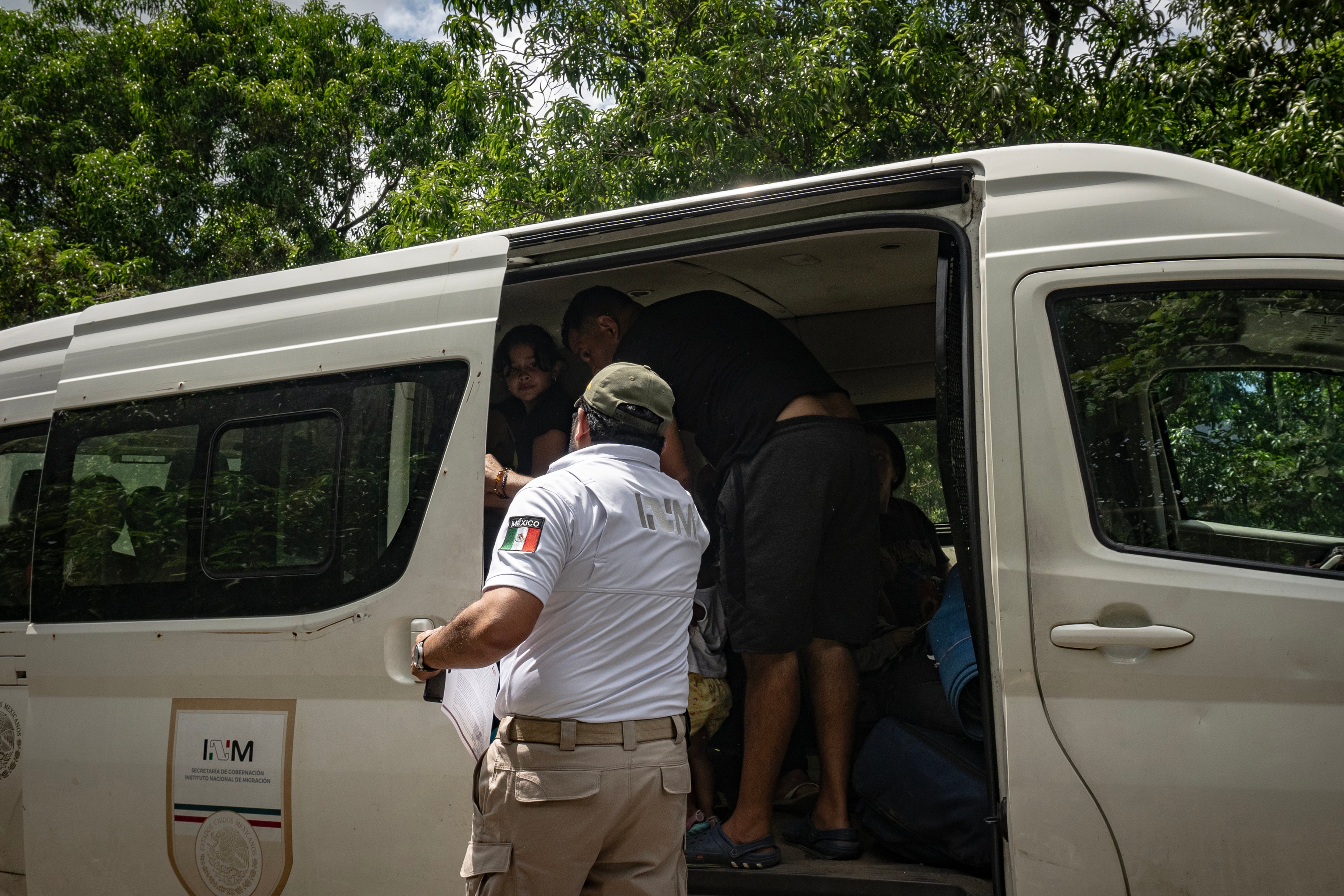 An officer from the National Migration Institute loads people of various nationalities into a government van to take them to the Siglo XXI migrant detention station.