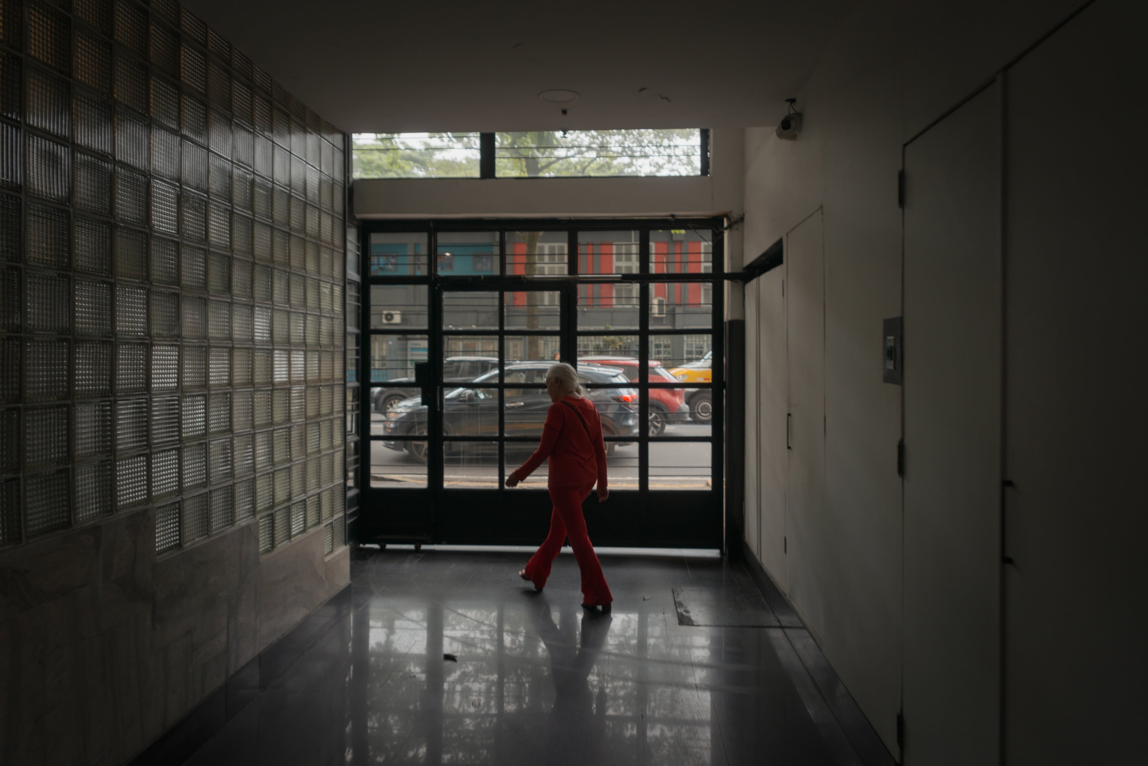 Ângela Valério walks alone down the hallway of the building where she lives, in Copacabana, Rio de Janeiro, Brazil.