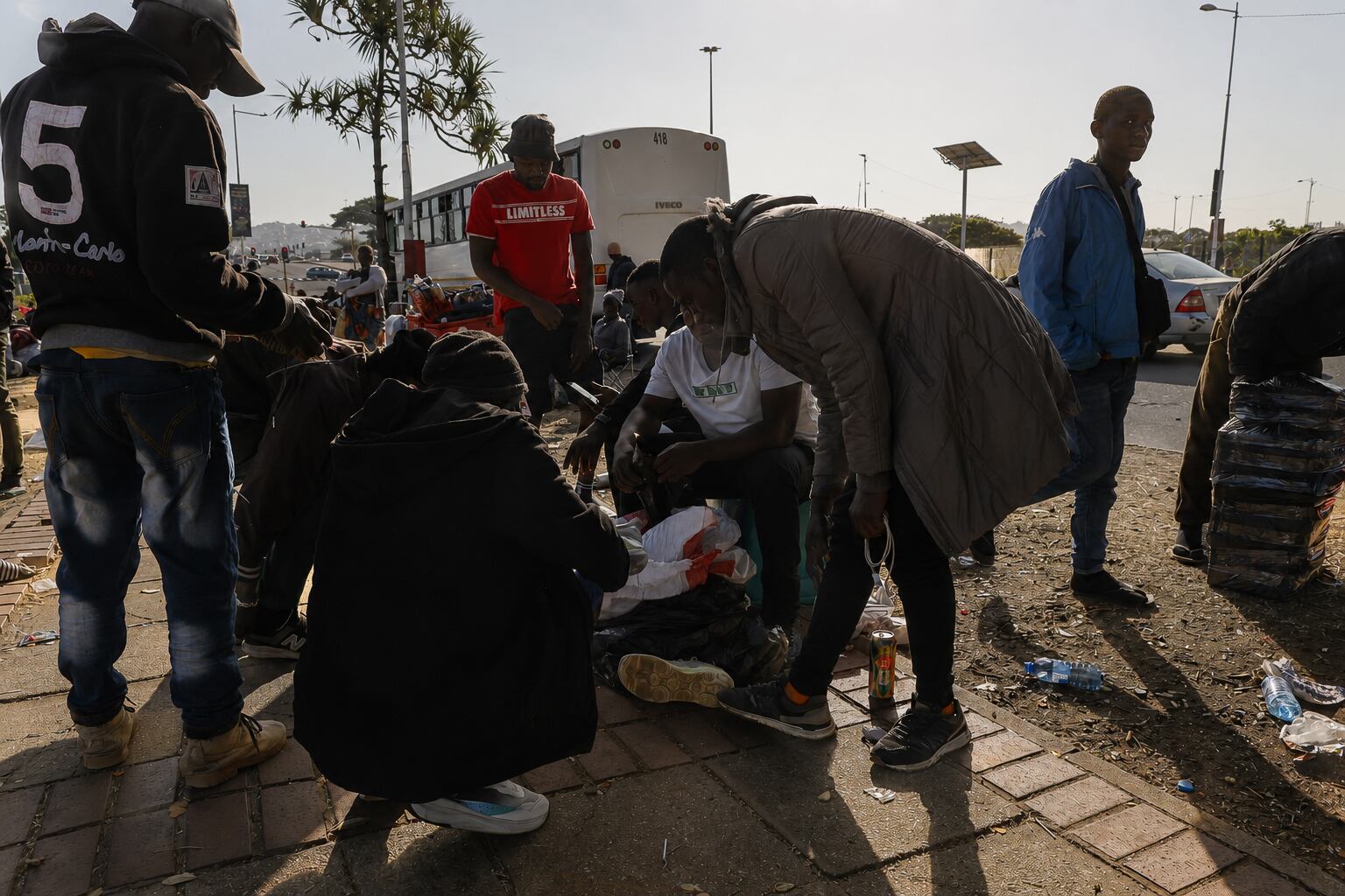 Jackson, an immigrant from Malawi, sells second-hand shoes to a group of fellos Malawians waiting to be sent back home, on July 5, 2026. 
