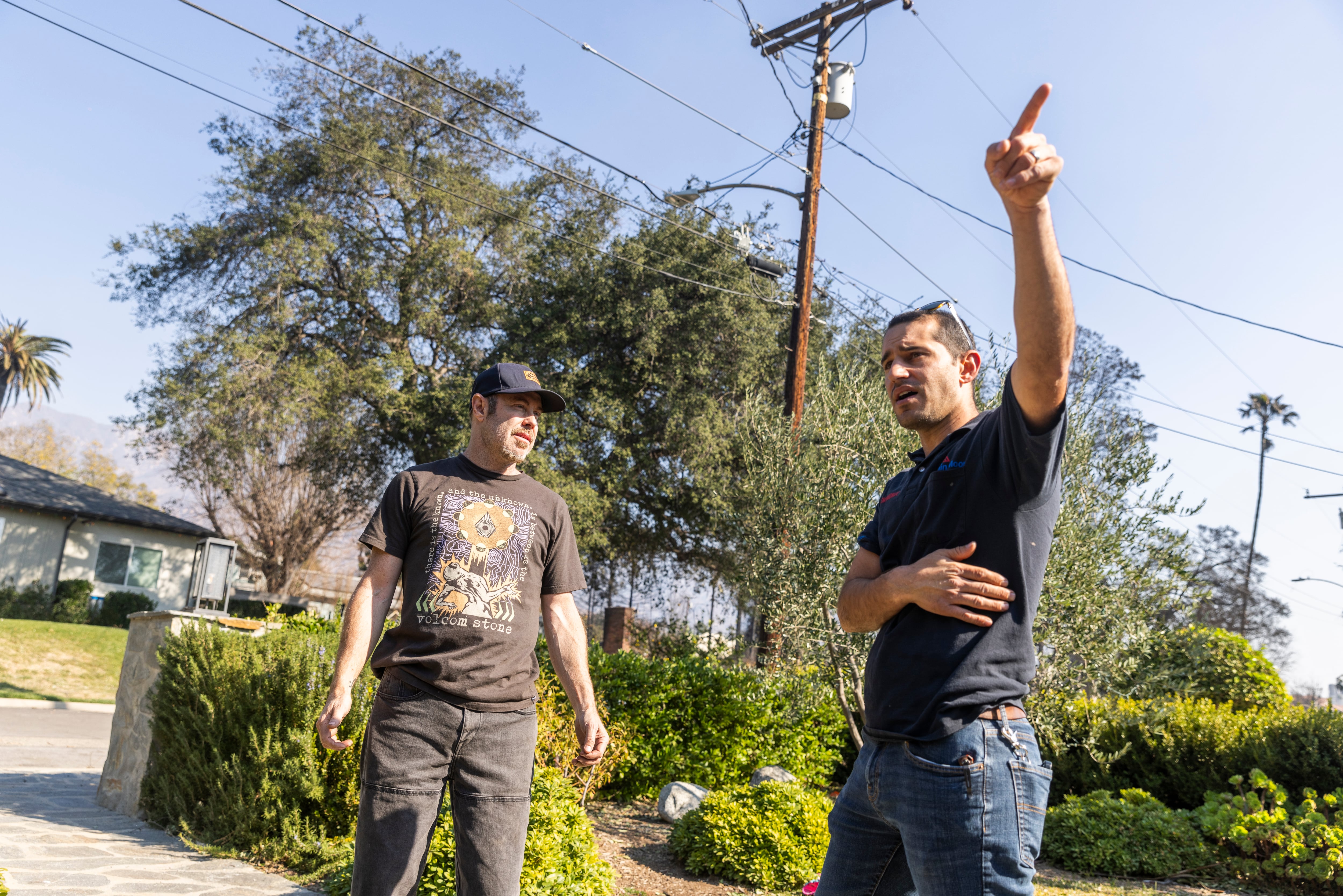 Shane Jordan (in cap) and his neighbor Rob, whose house he saved from the fire, chat for the first time since the fire in Altadena.