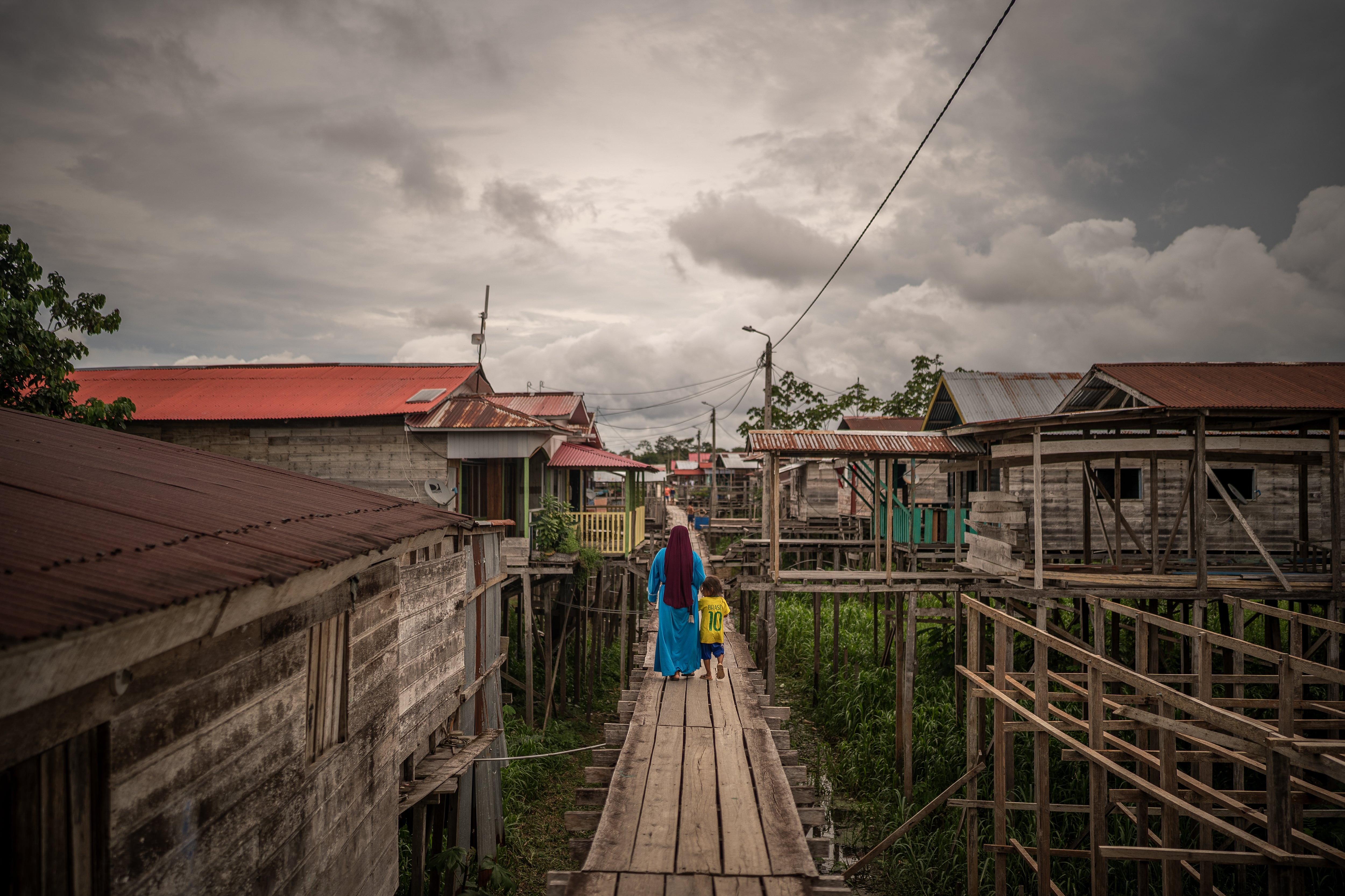 A woman walks with a child on the streets of the town of Iceland in the Peruvian Amazon, on December 12, 2024.