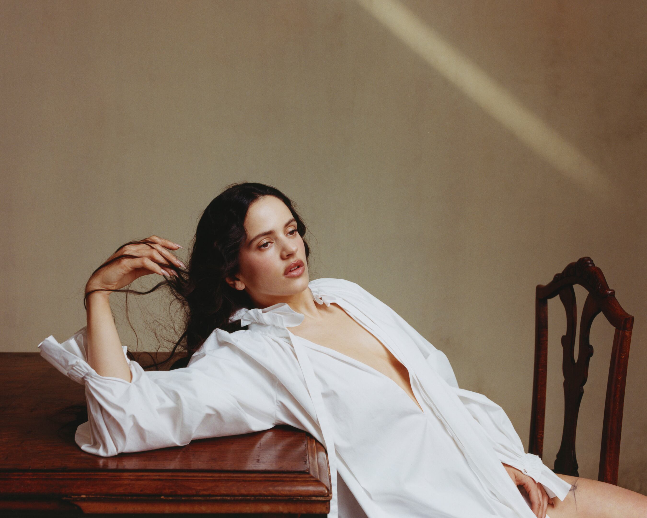 Rosalía wearing a white shirt with puffy sleeves and a ruffled collar, by Carolina Herrera.