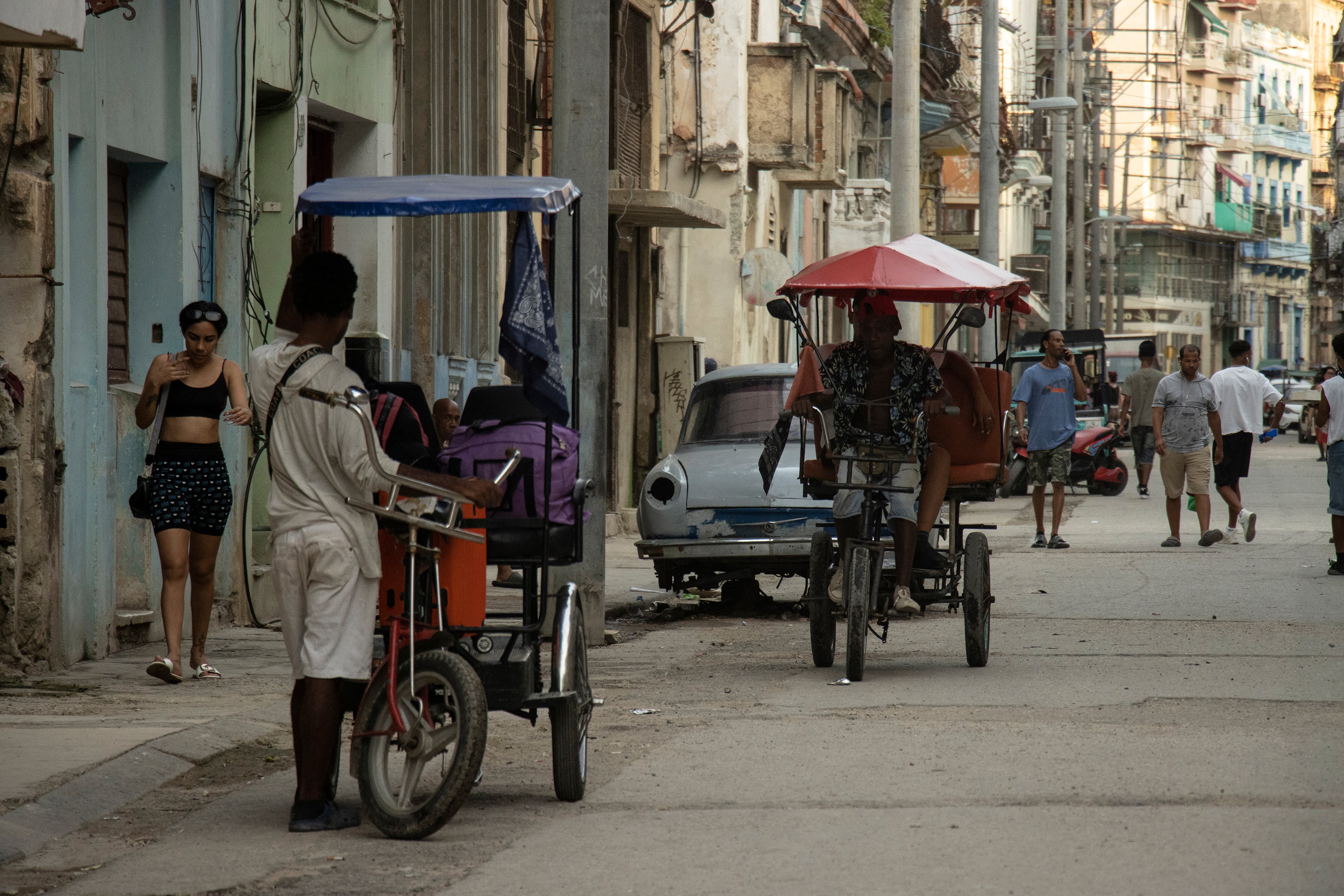 People ride rickshaws in downtown Havana.