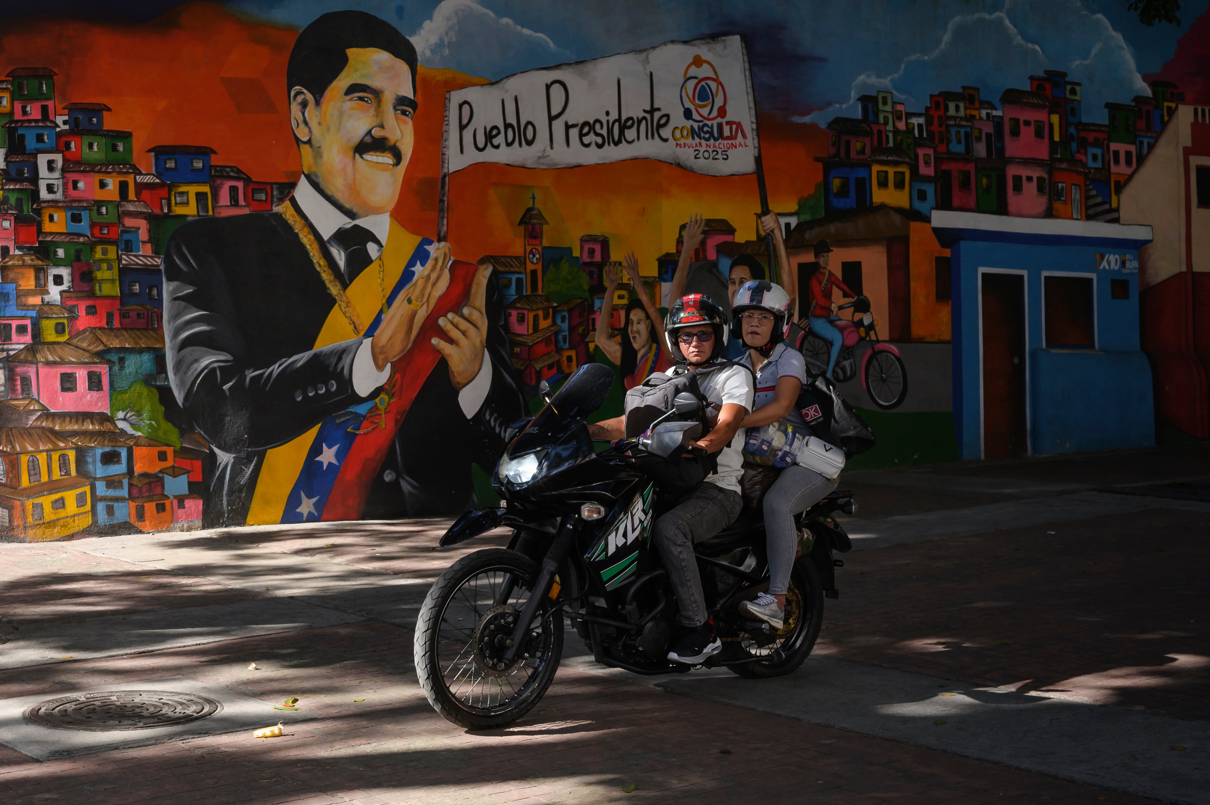 People walk past a mural of Nicolás Maduro in Caracas, Venezuela on November 22, 2025.