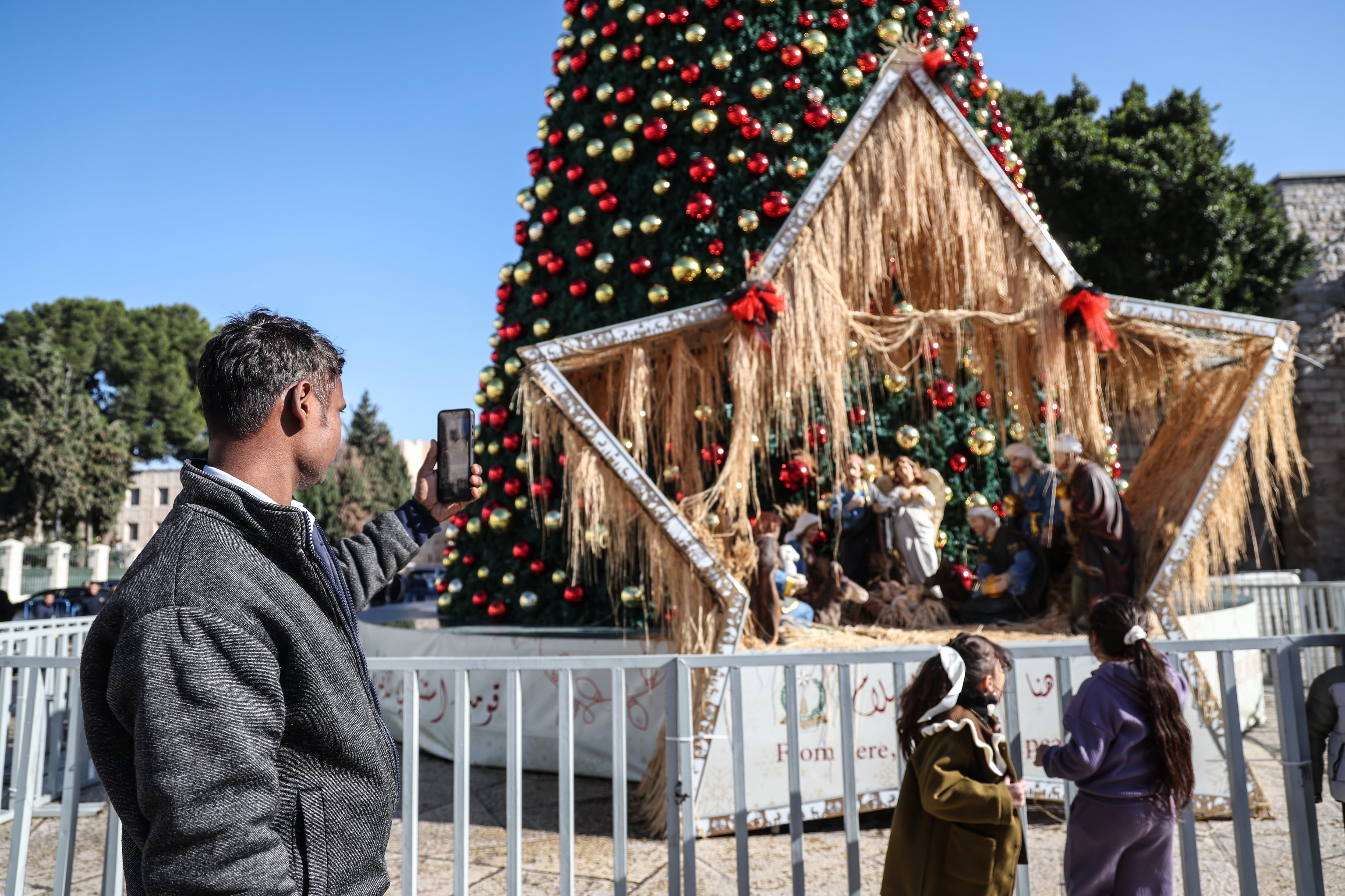A foreign visitor photographs the Christmas tree reinstalled in the Manger Square in Bethlehem, last Wednesday.