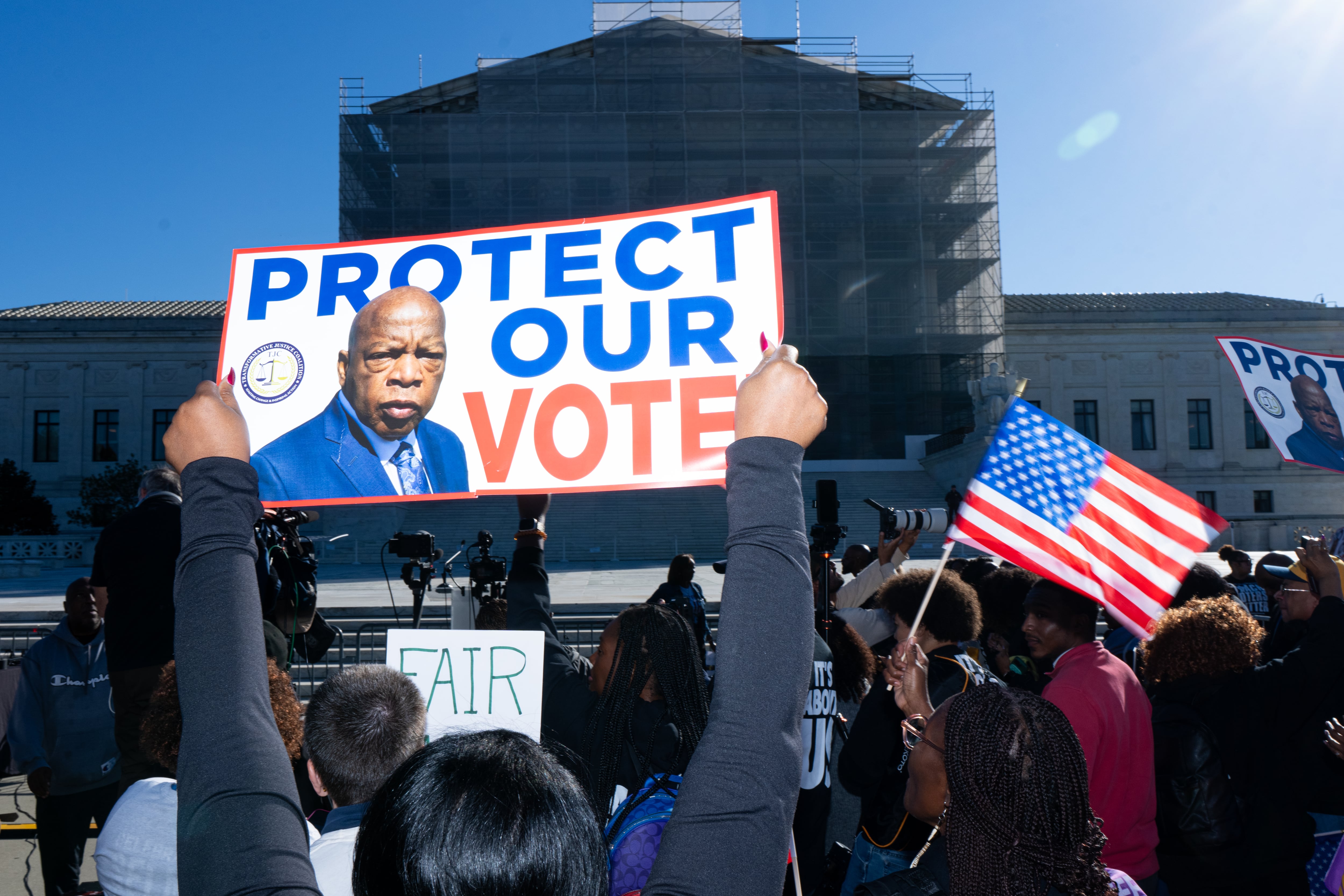 A protester holds up a sign reading “Protect Our Vote,” featuring the face of civil rights icon John Lewis, during a protest outside the Supreme Court on October 15.