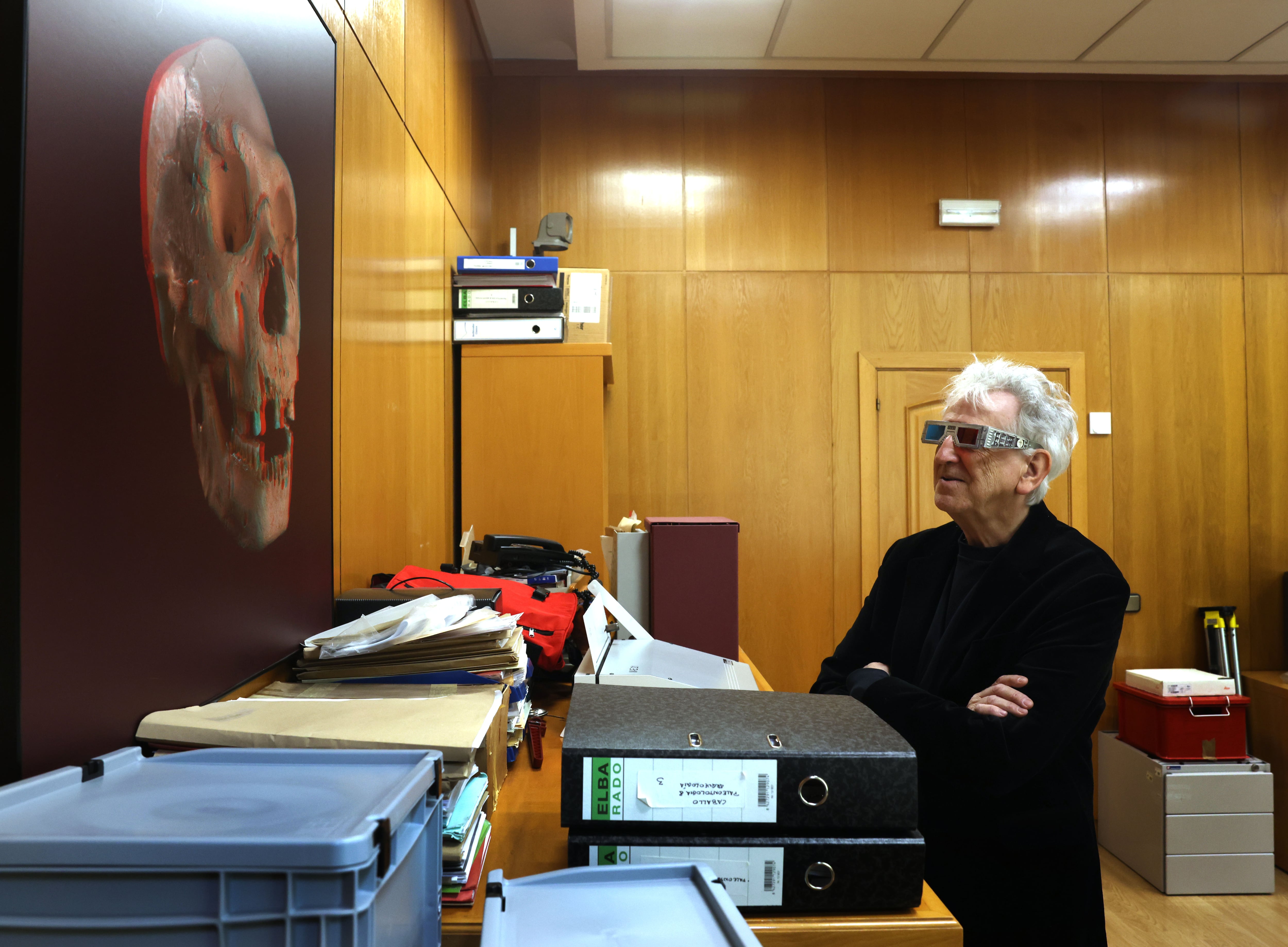 Arsuaga studies a three-dimensional reproduction of a skull using anaglyph glasses.