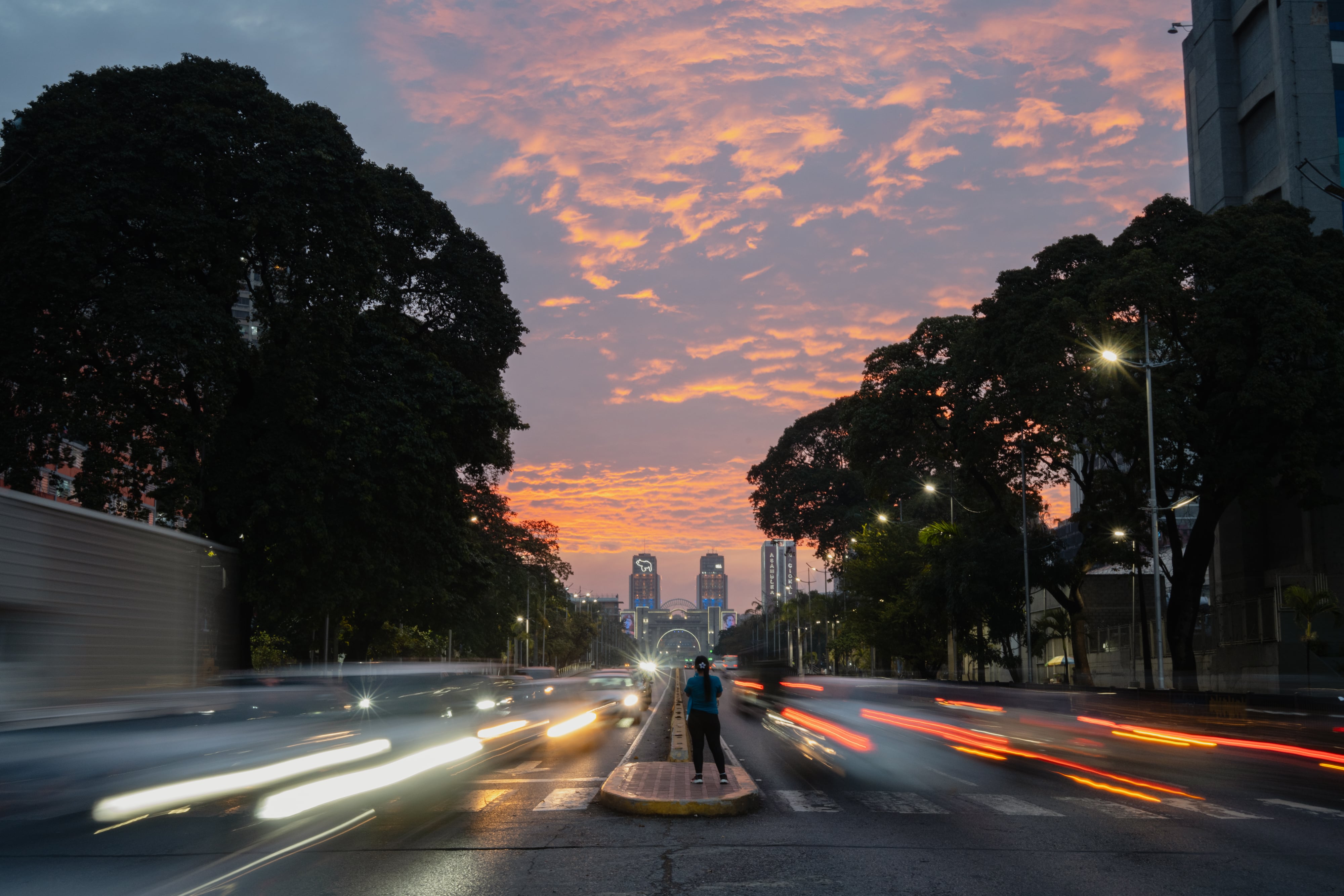 A woman watches the sunset on Bolivar Avenue.