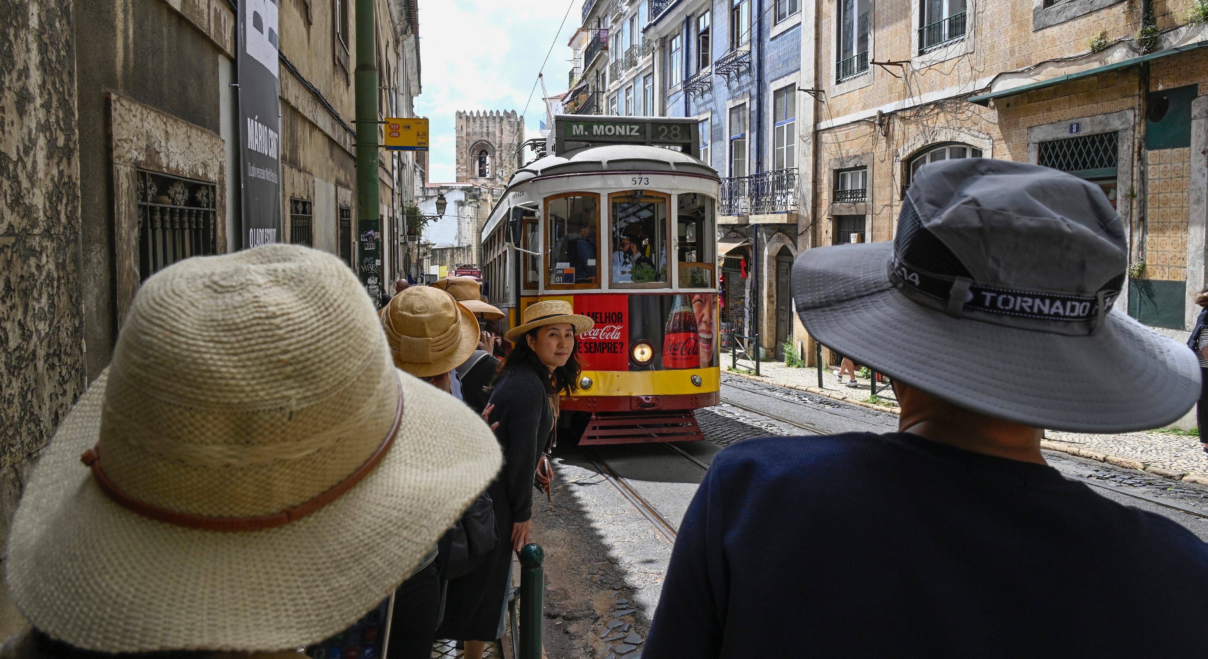 Tourists wait for the arrival of the line 46 tram on Augusto Rosa Street, in the historic center of Lisbon.