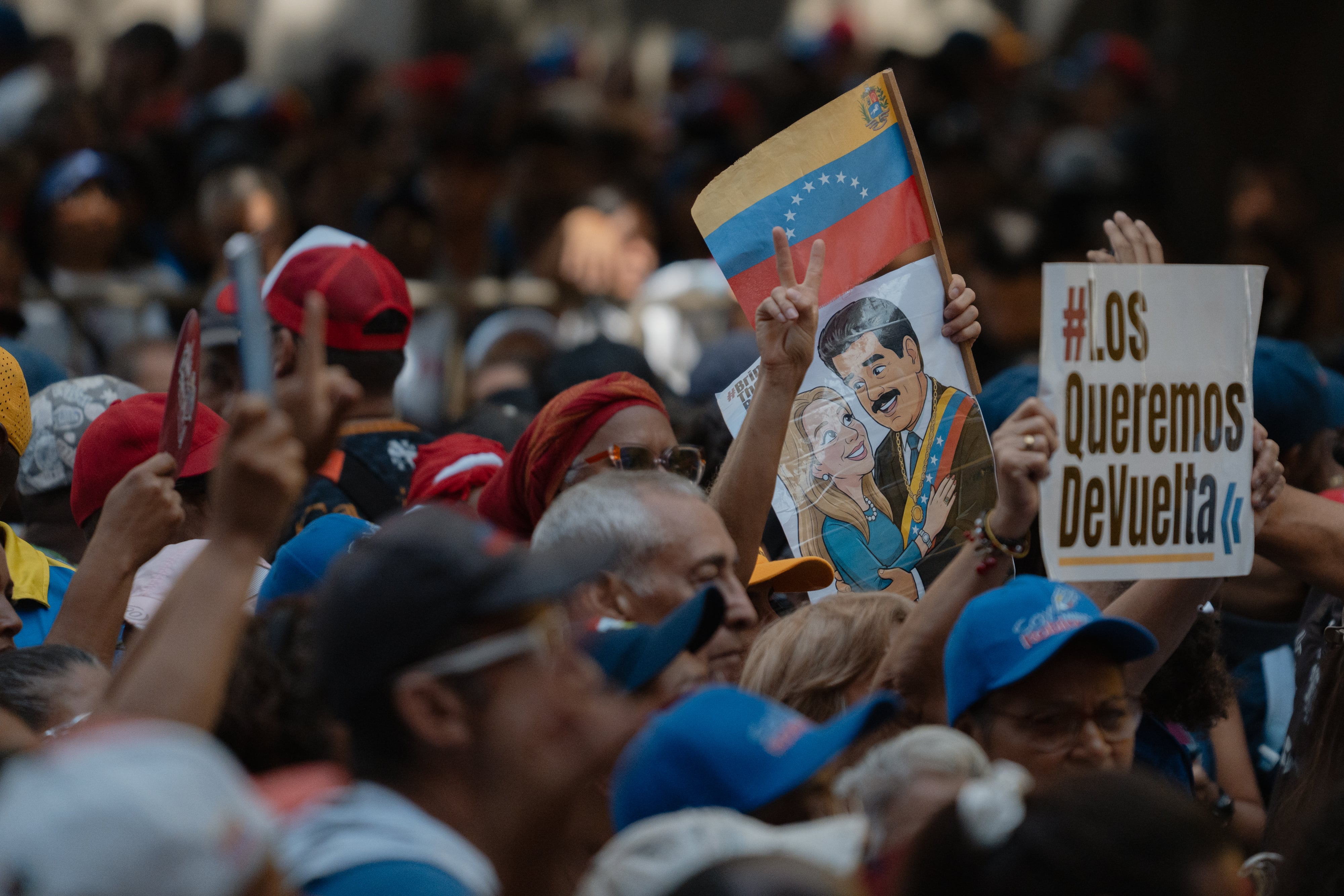 A woman holds a sign with images of Nicolás Maduro and Cilia Flores at the peace march.