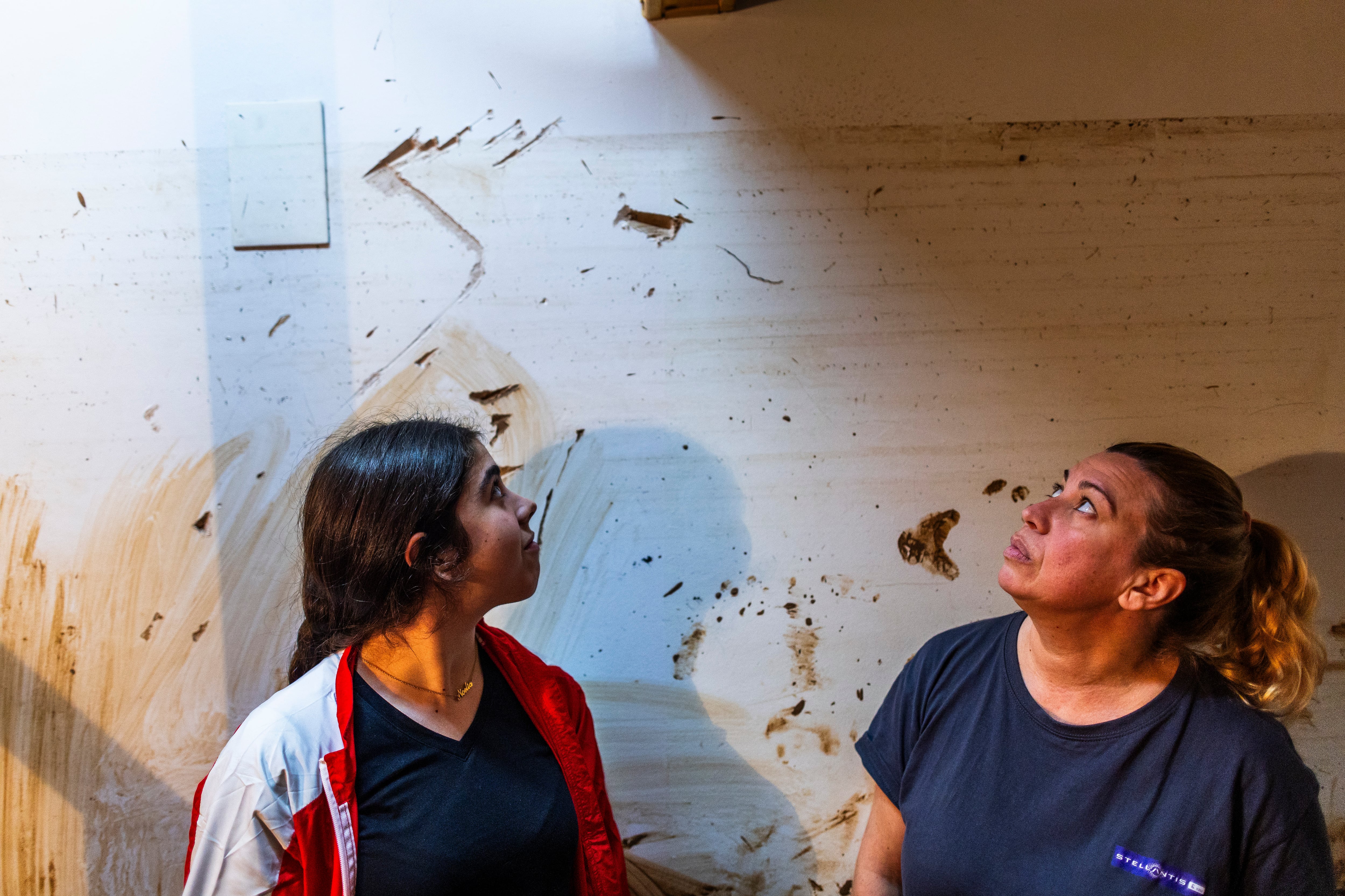 Pilar Pérez, owner of the Azabache hair salon, and her daughter Noelia, look at the mark that indicates how high the water reached on the day of the flood.