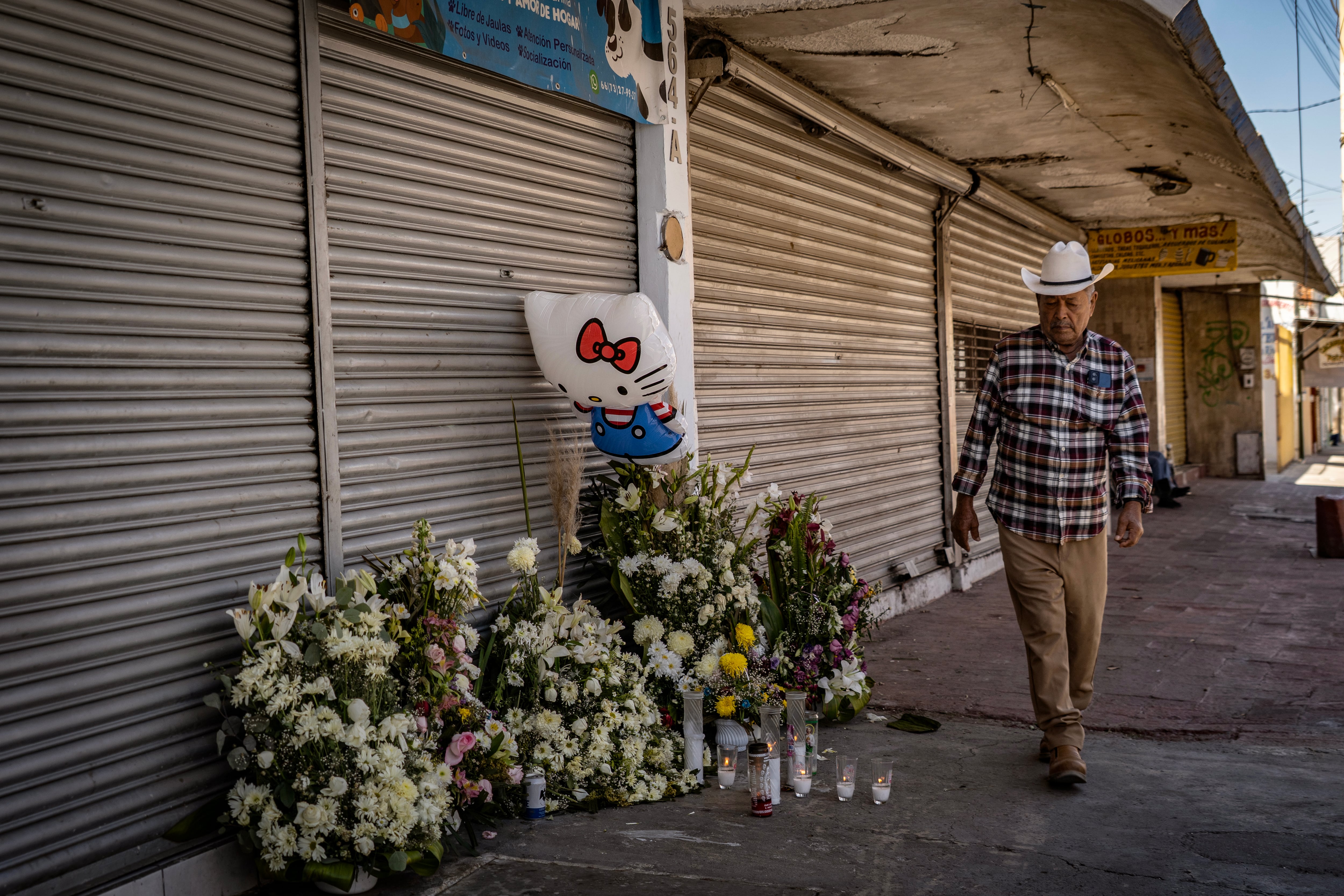 A man stands in front of an altar erected in memory of four women who were attacked by a gunman.