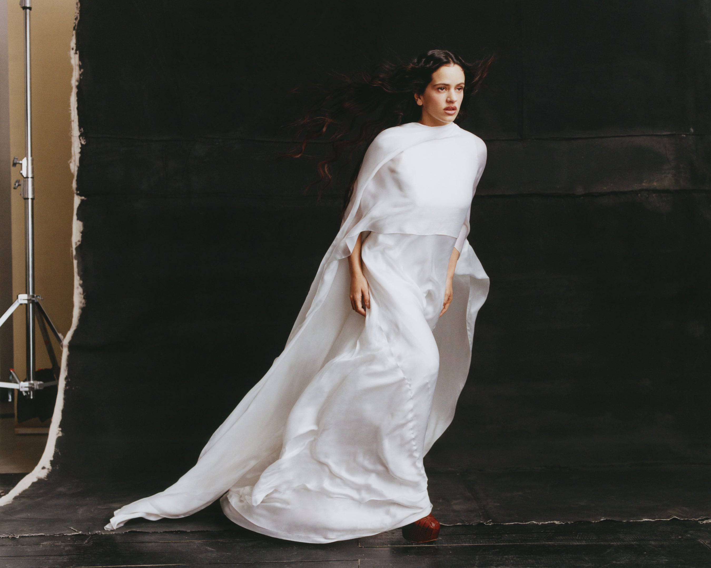 Rosalía wearing a flowing white layered dress by Cortana and brown platform shoes by Vivienne Westwood.