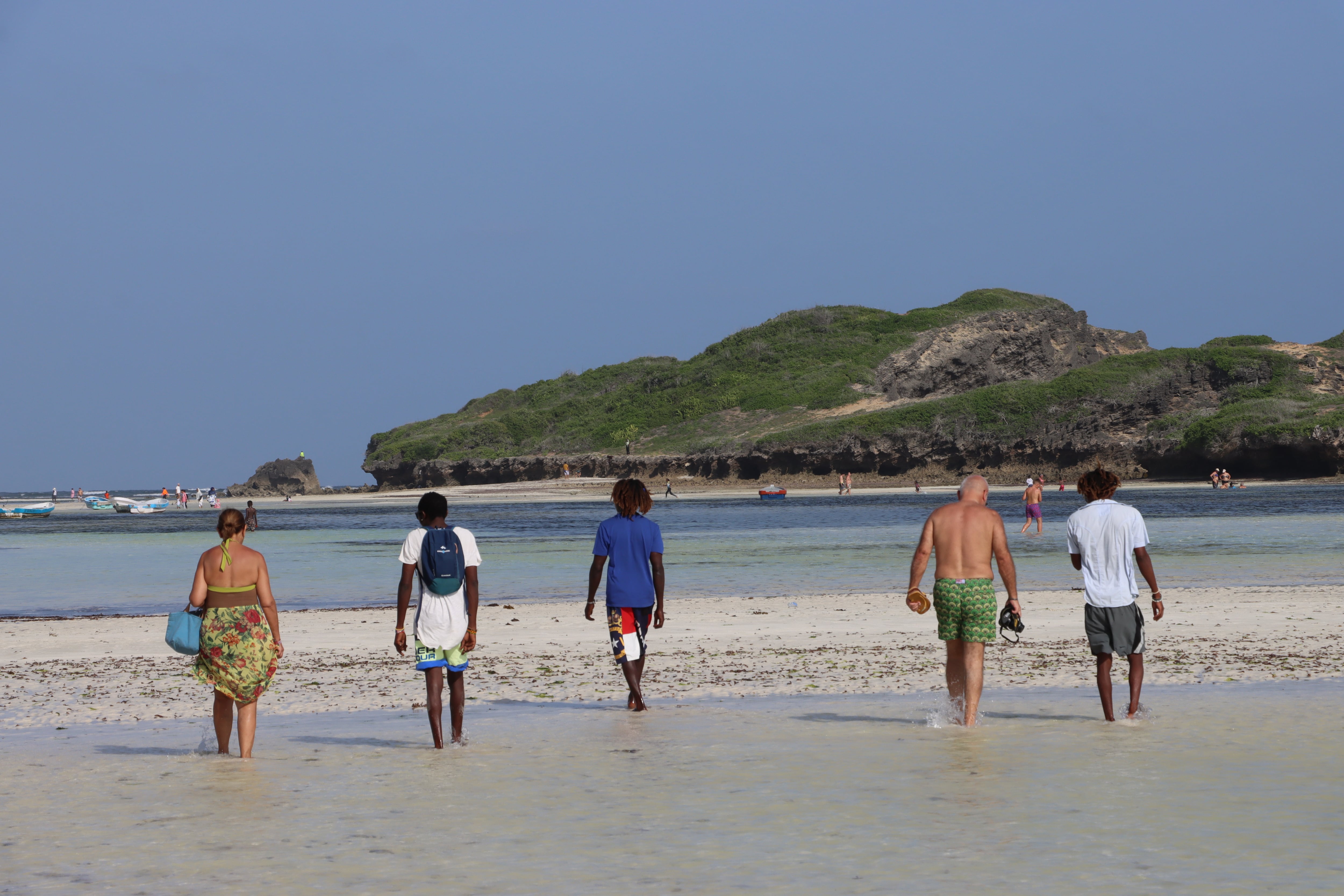Three beach boys accompany a European tourist couple at a Watamu beach on December 25, 2024.