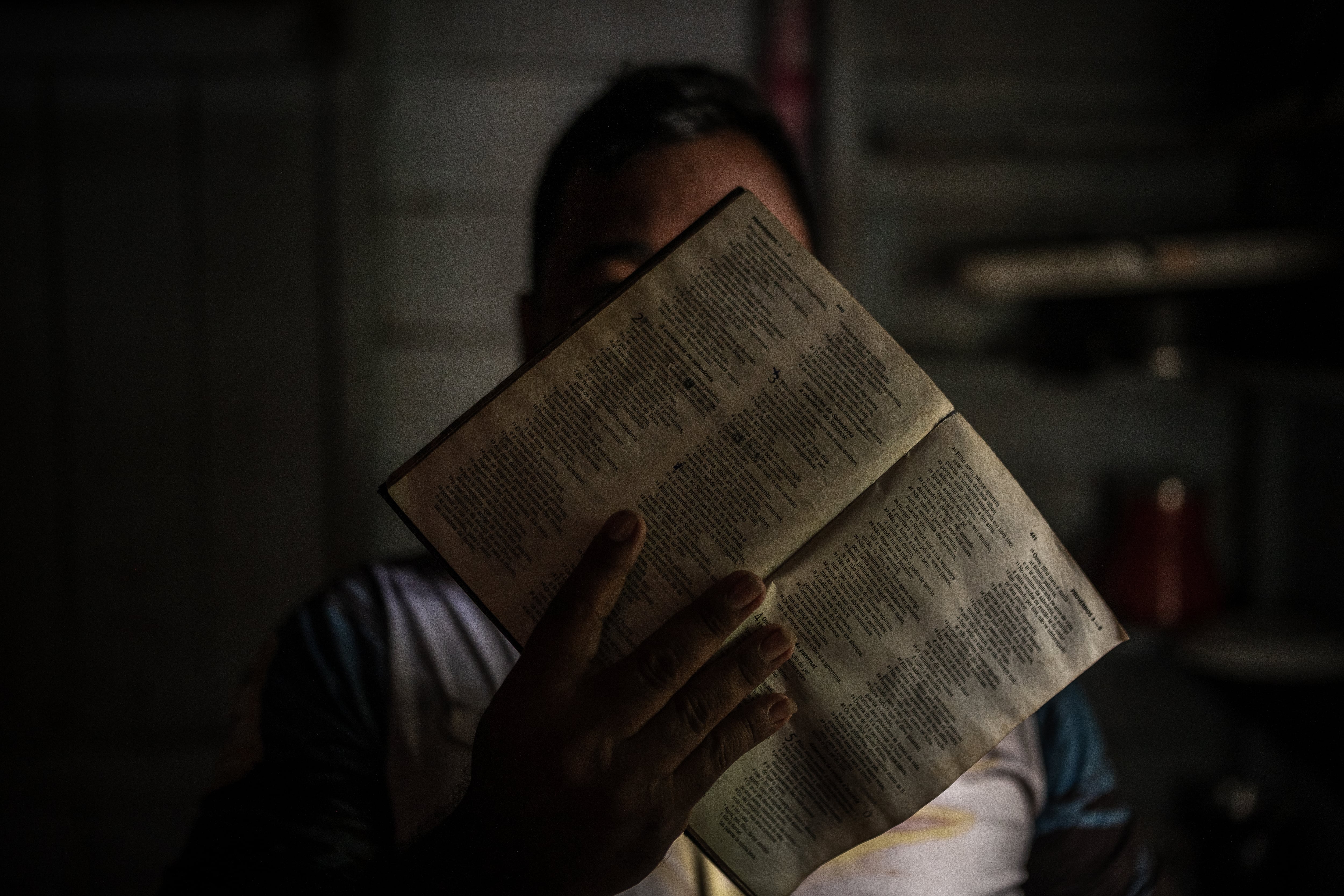 The pastor of an evangelical church covers his face with a Bible to protect his identity in Benjamin Constant, a city in the Brazilian Amazon.