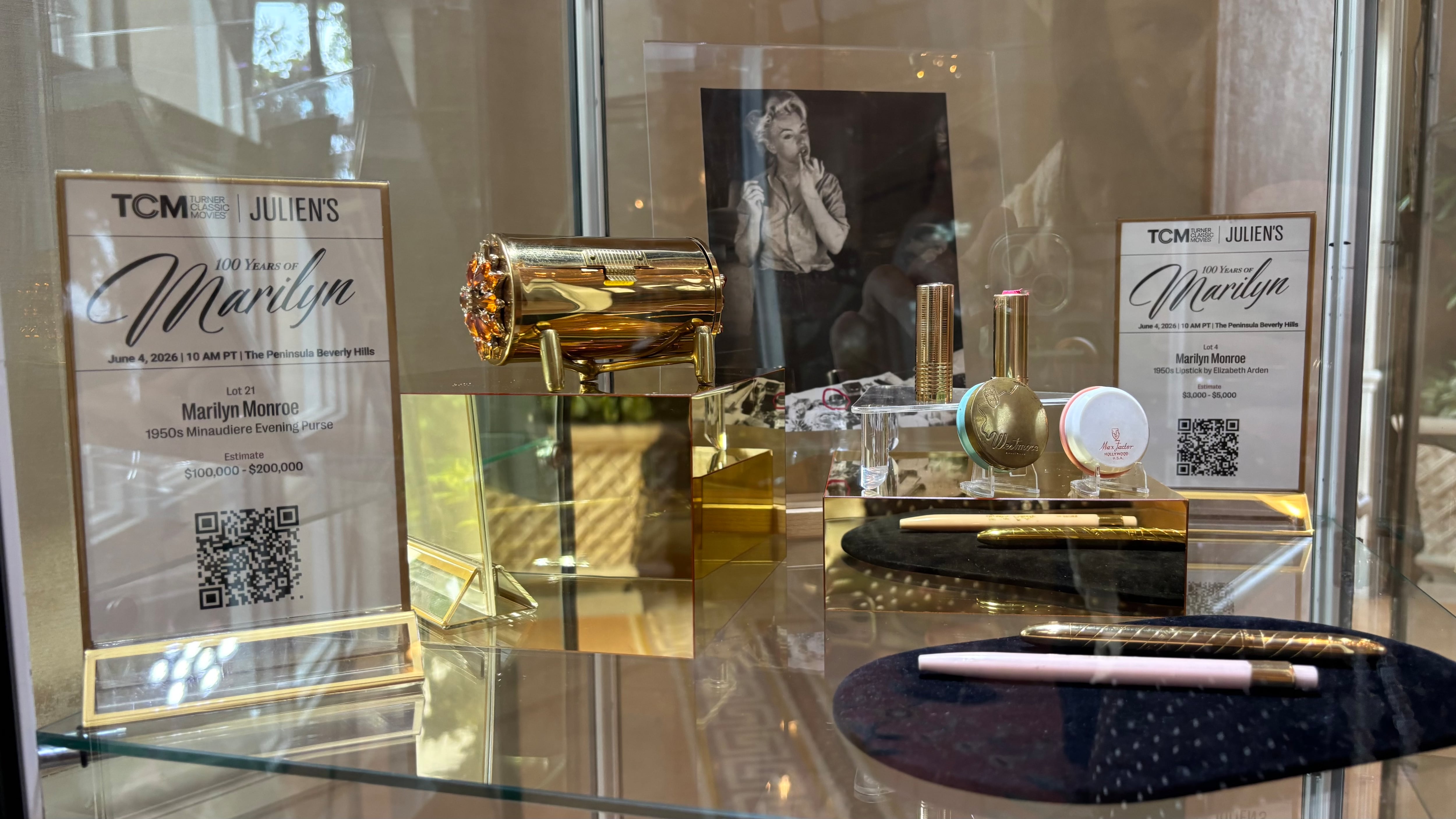 Several items belonging to Marilyn Monroe were on display at the Julien's Auctions sale held at the Peninsula Hotel in Beverly Hills on June 4, 2026. On the left, a gold handbag; on the right, from top to bottom, lipsticks, a round lipstick, mascara, and an eyeliner pencil.