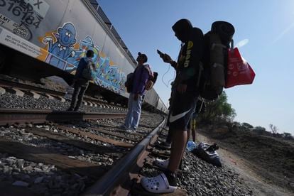 Migrants watch a train go past as they wait along the train tracks hoping to board a freight train heading north