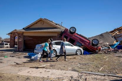 Neighbors walk in front of a home damaged at Wheatland Drive and Conway Drive on Monday, Feb. 27, 2023 in Norman, Okla.