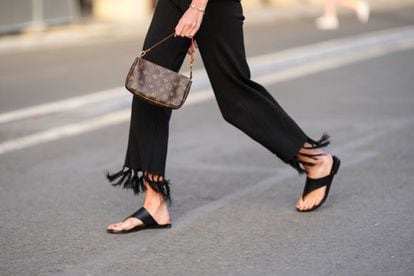 Amanda Derhy trägt eine Umhängetasche aus beschichtetem Canvas von Louis Vuitton mit einem braunen, glänzenden Monogramm-Druckmuster. 