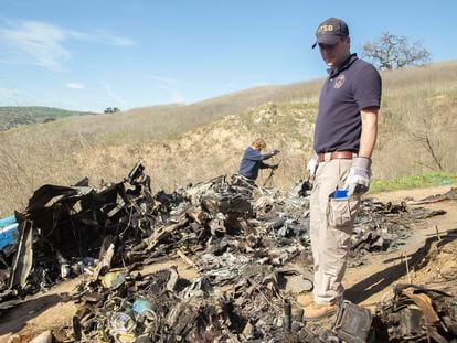 An investigator inspects the remains of the crashed helicopter in Calabasas, where Kobe Bryant and eight others died in January 2020.
