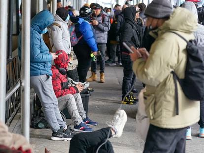 Recent immigrants to the United States sit with their belongings on the sidewalk in front of the Watson Hotel in New York, Monday, Jan. 30, 2023.