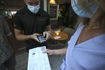 Un trabajador comprueba el certificado covid de un cliente en Córcega