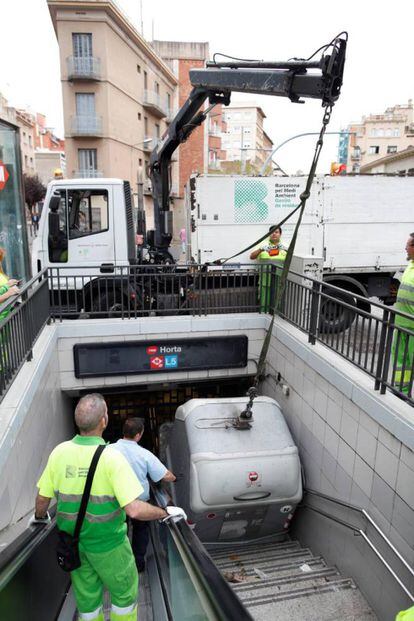 A trash container blocking the entrance to the Horta Metro station in Barcelona is removed by workers on Friday.