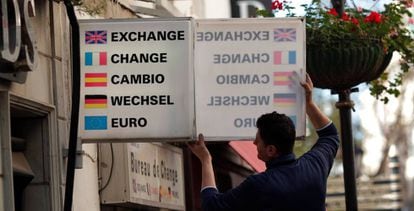 A worker puts up a sign over a currency exchange counter in Gibraltar.