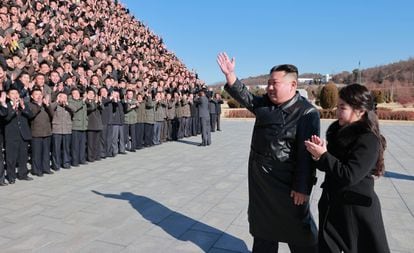 Kim Jong-un and reportedly his middle daughter greet a group of scientists working on the missile program, in an undated photo released on November 27 by the North Korean regime.