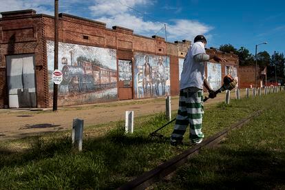 A convict from the prison of Parchman cuts the grass next to the mural alluding to Handy's meeting where the old Tutwiler station was located.