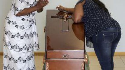 The mother of Samba, Clementine Nijba (l), weeps next to the coffin of her daughter.