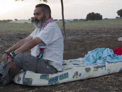 Juan Manuel S&aacute;nchez Gordillo sits on the mattress where he is sleeping on land owned by the Defense Ministry. 