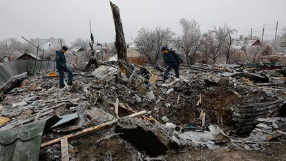 Two officials inspect the ruins of a house destroyed by bombing in the Ukrainian town of Yasynuvata.