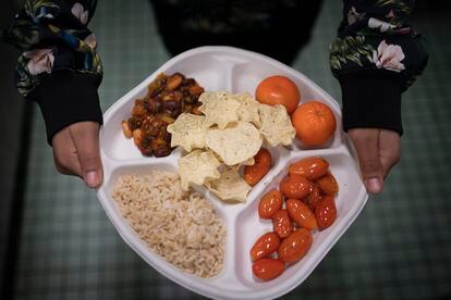 A seventh grader carries her plate which consists of three bean chili, rice, mandarins and cherry tomatoes and baked chips during her lunch break at a local public school, Friday, Feb. 10, 2023, in the Brooklyn borough of New York.