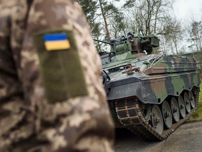 A Ukrainian soldier is standing in front of a Marder infantry fighting vehicle at the German forces Bundeswehr training area in Munster, Germany, Monday, Feb. 20, 2023.