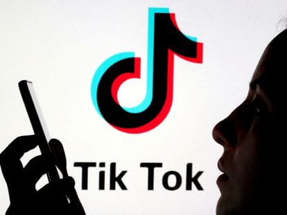 A person holds a smartphone as Tik Tok logo is displayed behind in this picture illustration taken November 7, 2019.